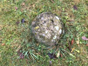 Runder Stein im Gras liegend