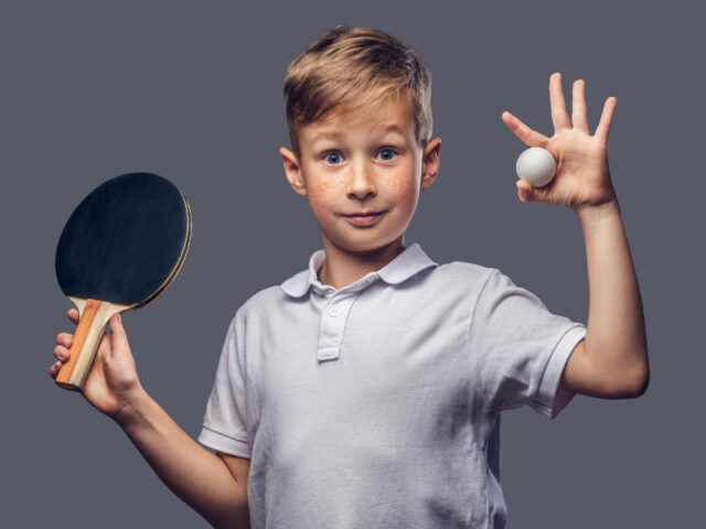 Junge hält einen Tischtennisball und Schläger